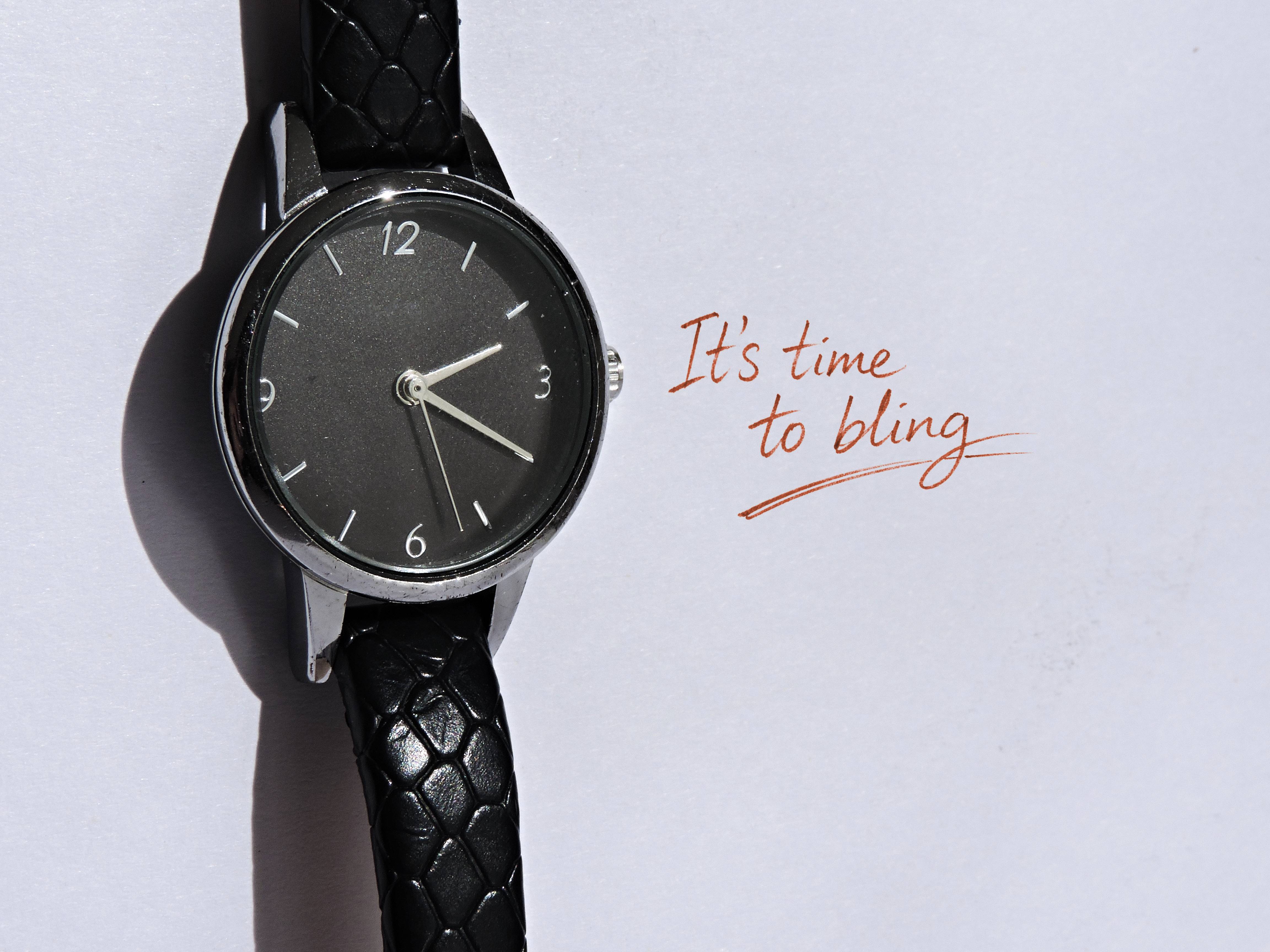 Reloj negro sobre papel con la nota manuscrita &ldquo;It&rsquo;s time to bling&rdquo;