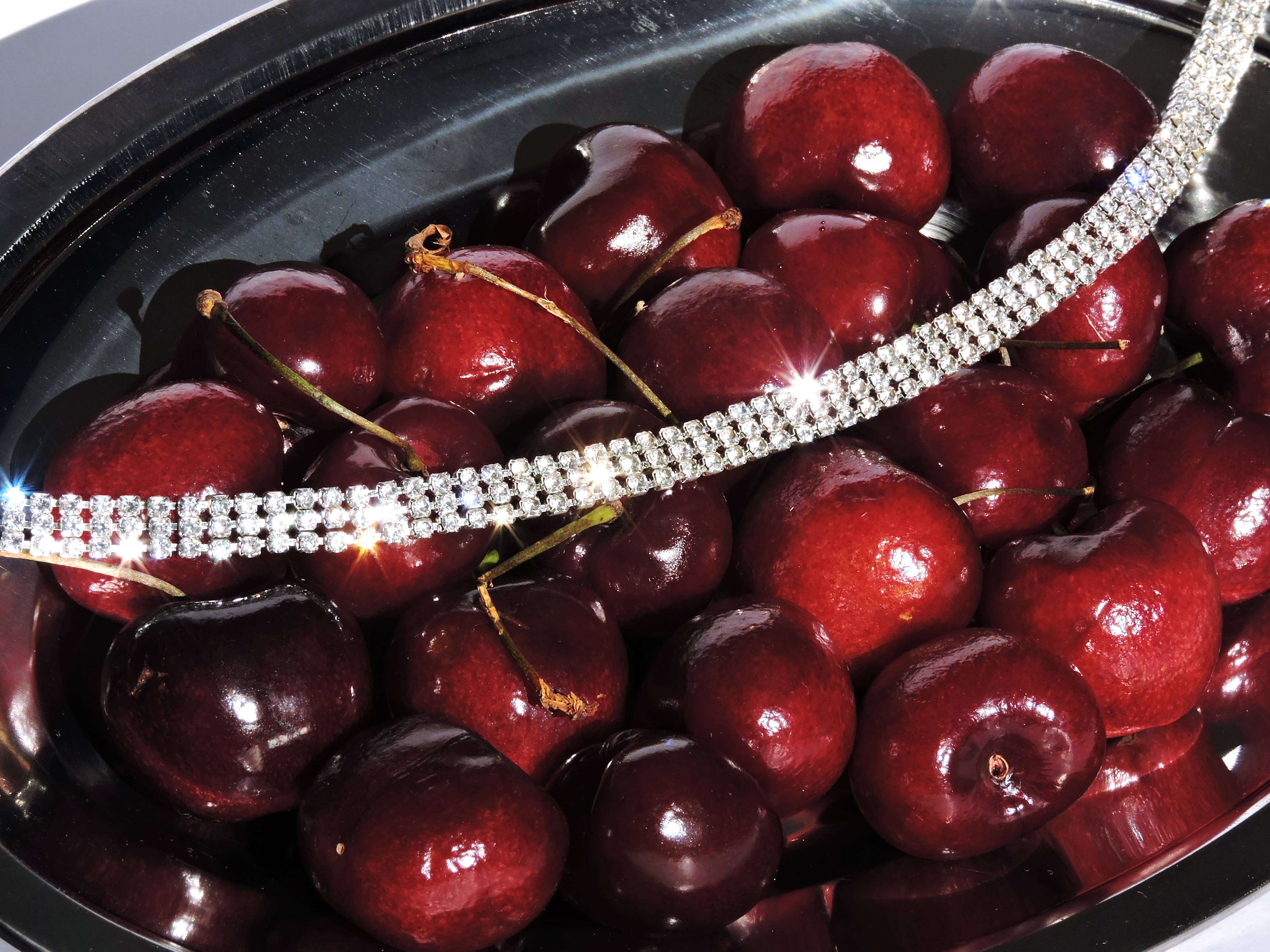 Cerezas con una pulsera de strass en un cuenco oscuro