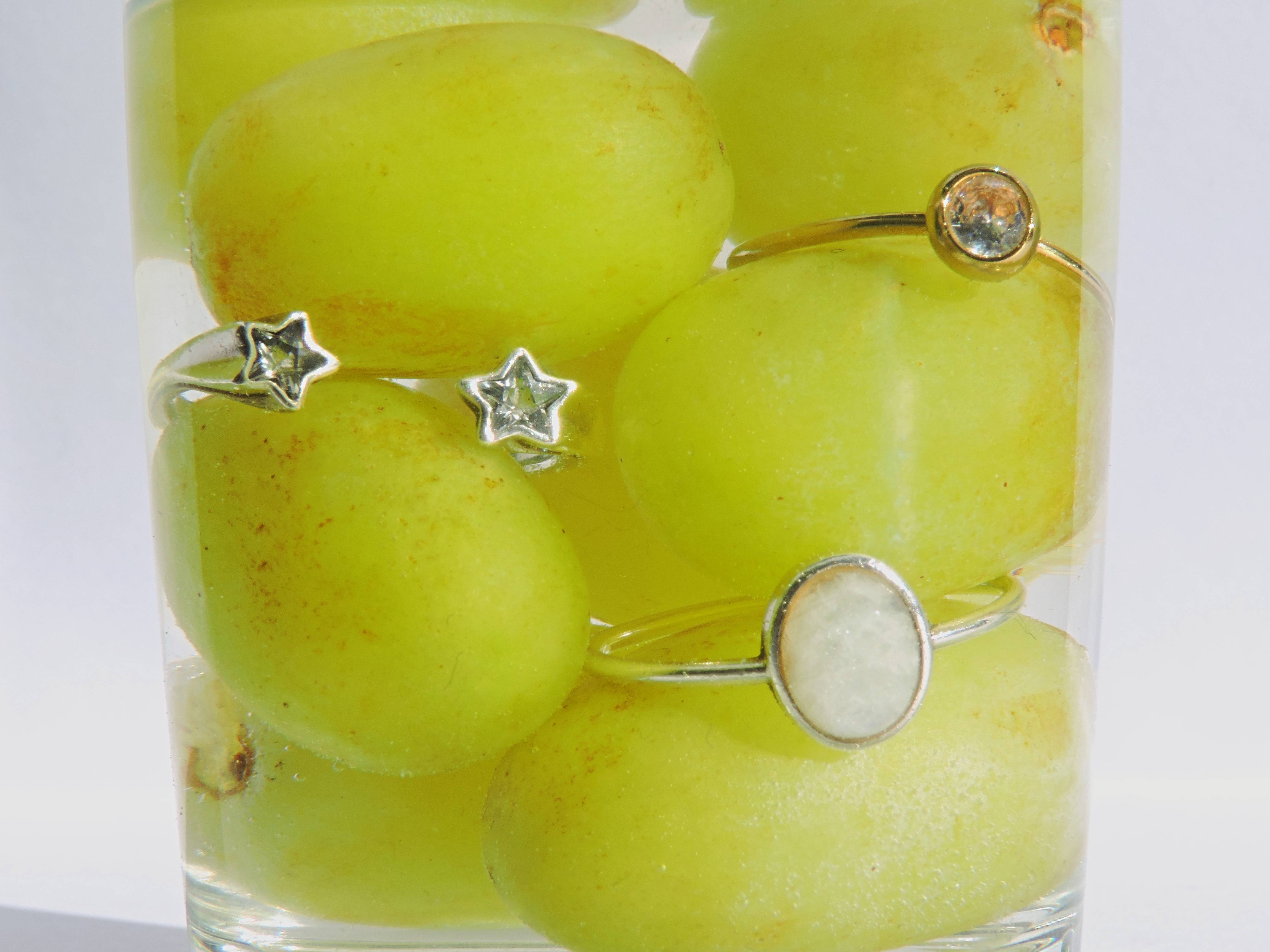 Uvas verdes en un vaso con anillos de estrella y de piedra