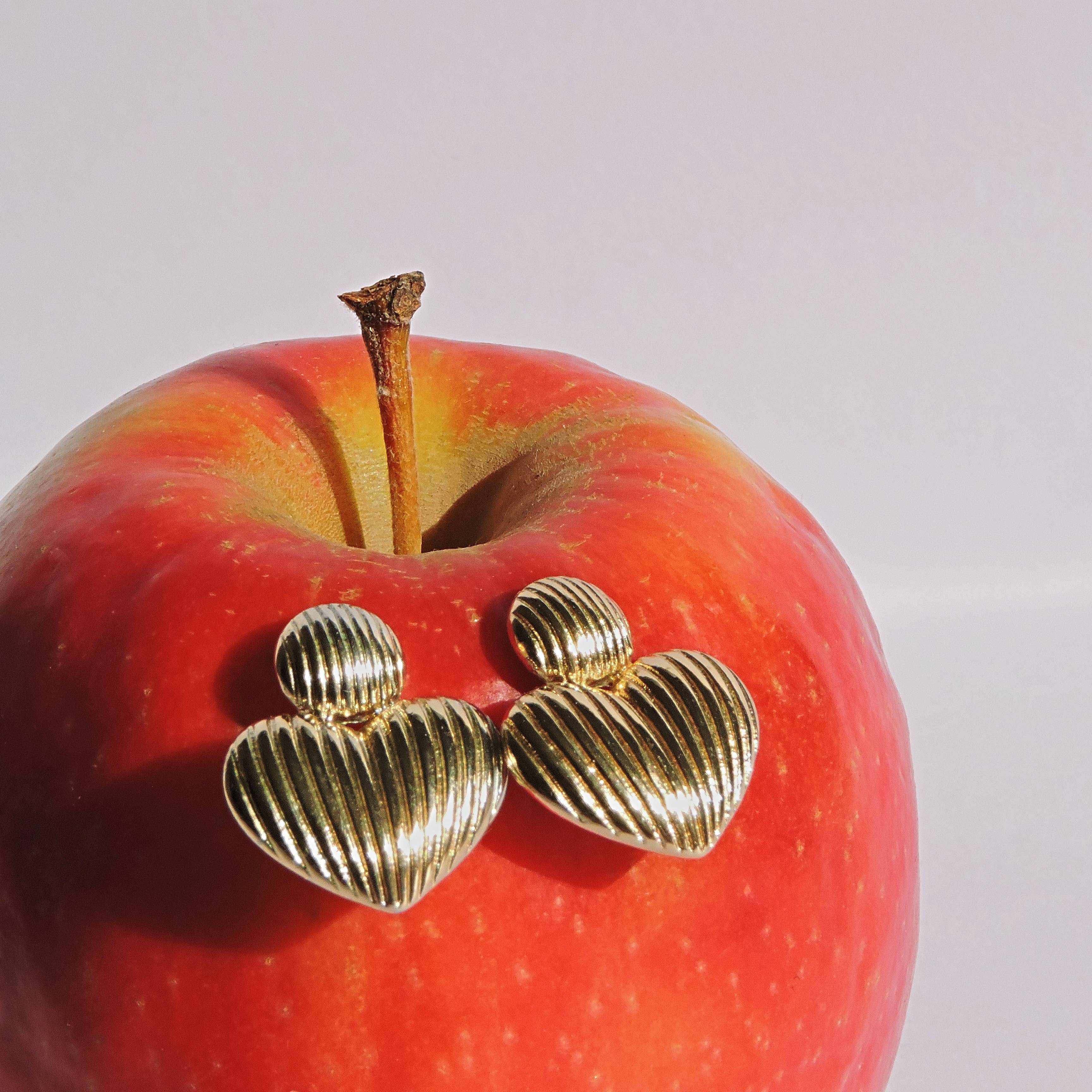 Manzana roja con pendientes dorados en forma de corazón