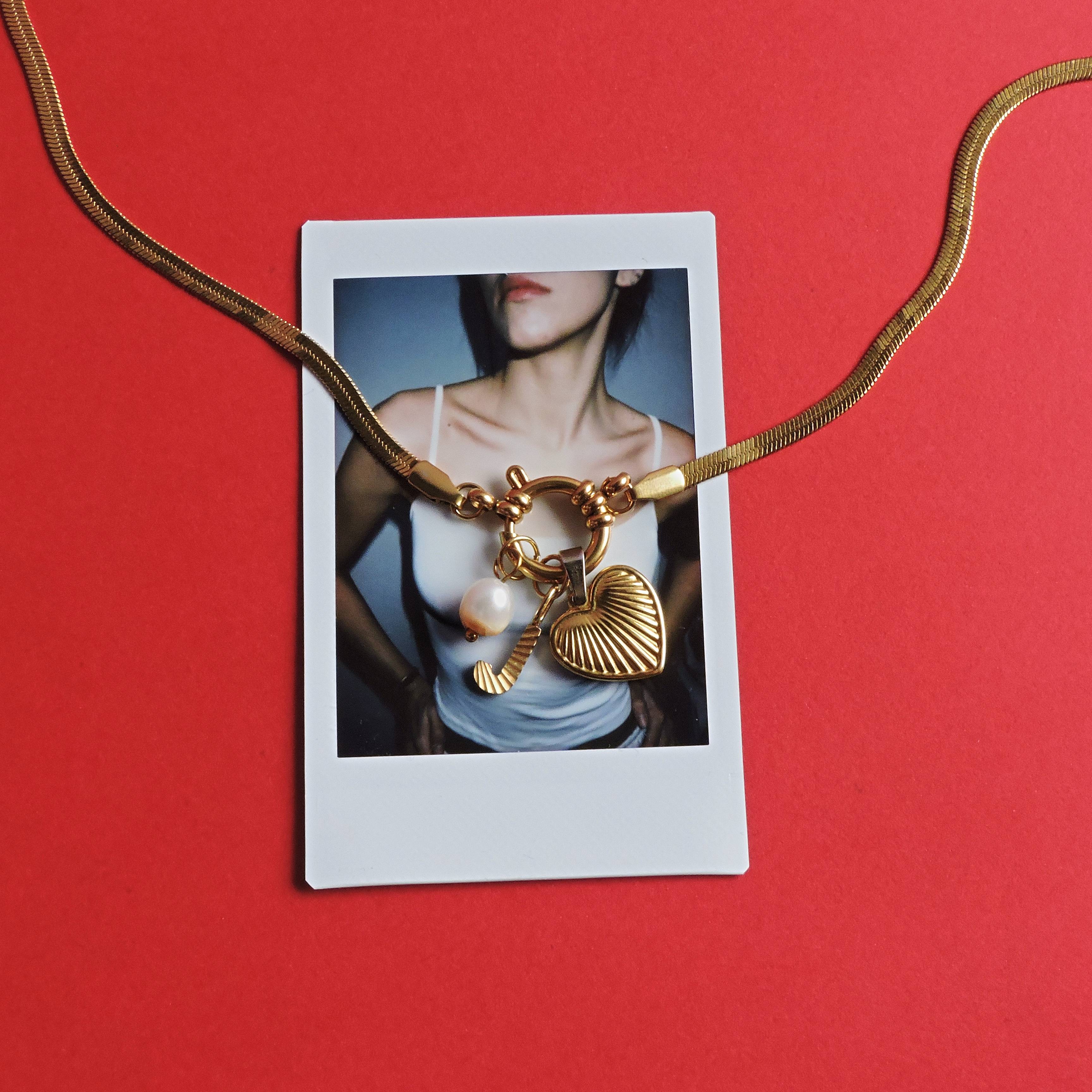 Polaroid sobre fondo rojo con un collar de colgante dorado